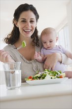 Mother and baby boy (2-5 months) eating salad. Photo : Jamie Grill
