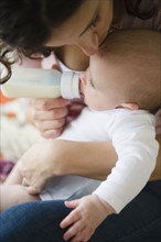 Mother feeding baby boy (2-5 months) using feeding bottle. Photo : Jamie Grill