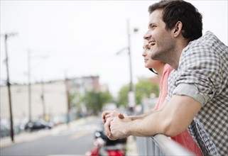 USA, New Jersey, Jersey City, Profile of happy young couple leaning on fence. Photo : Jamie Grill
