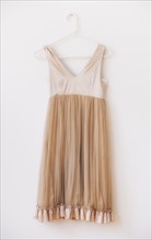 Dress with frill on hanger against white wall. Photo : Daniel Grill