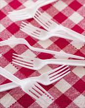 Plastic forks on checked tablecloth. Photo : Daniel Grill