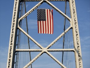USA, New York City, American flag flowing on bridge span. Photo : fotog