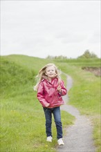 Girl in pink raincoat on country path. Photo : Mike Kemp