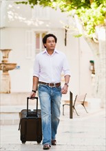 France, Cassis, Man walking with suitcase. Photo : Mike Kemp