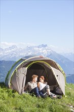 Switzerland, Leysin, Hikers resting in tent pitched on meadow. Photo: Mike Kemp
