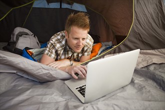 Hiker in tent using laptop. Photo : Mike Kemp
