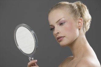 Beauty portrait of woman looking in mirror. Photo : Jan Scherders