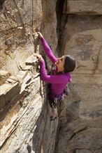 Smiling woman rock climbing. Photo : Noah Clayton