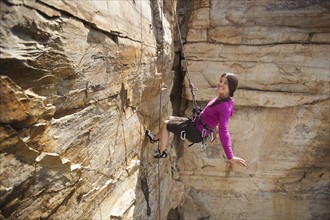 Smiling woman rock climbing. Photo: Noah Clayton