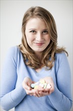Studio shot of smiling woman holding heart-shaped sweets. Photo: Jessica Peterson
