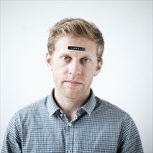 Studio shot of young man with word 'lonely' on forehead. Photo: Jessica Peterson