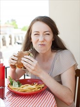 Portrait of young woman having burger. Photo: Jessica Peterson