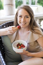 Portrait of young woman having strawberry. Photo : Jessica Peterson