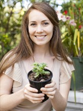 Portrait of young woman with flower in pot. Photo : Jessica Peterson