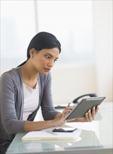 Businesswoman using digital tablet in office.