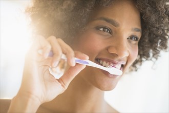 Beauty portrait of woman brushing teeth, studio shot.