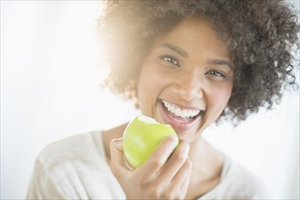 Portrait of woman eating apple, studio shot.