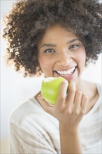 Portrait of woman eating apple, studio shot.