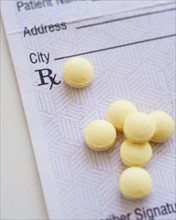 Yellow pills with prescription form, studio shot.