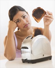 Studio shot of woman holding burnt toast.