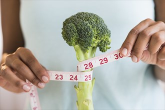 Woman measuring broccoli .