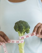 Woman measuring broccoli .