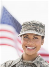 Portrait of female army soldier, American flag in background.
