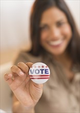 Woman holding vote button.