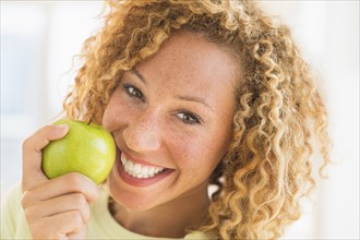 Portrait of smiling young woman with apple.