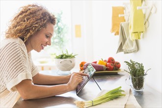 Young woman using digital tablet in kitchen.