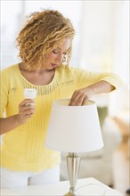 Young woman changing bulb in lamp.
