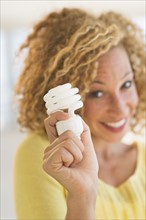 Portrait of smiling young woman holding light bulb.