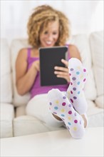 Young woman sitting on sofa with digital tablet.