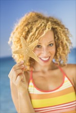 Portrait of young woman holding starfish.