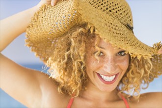Portrait of smiling young woman in sun hat.