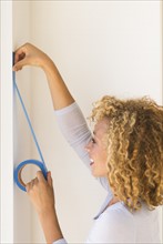 Young woman applying duct tape on wall.