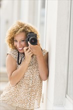 Portrait of young woman holding camera.