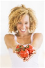 Portrait of young woman holding tomatoes.
