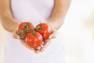 Portrait of young woman holding tomatoes.