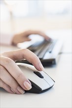 Close up of woman's hands using computer keyboard and computer mouse.
