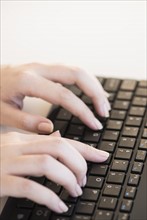Close up of woman's hands typing on computer keyboard .
