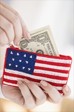 Woman holding banknotes and purse with american flag on it.