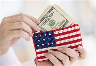 Woman holding banknotes and purse with american flag on it.