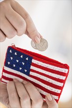 Woman holding coins and purse with american flag on it.