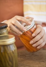 Woman closing jar with pickled vegetables.