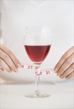 Woman measuring glass with rose wine.