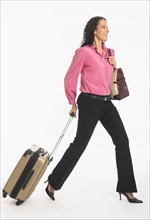 Studio shot of woman walking with suitcase.