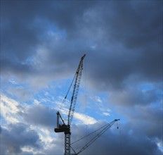 Construction cranes on cloudy sky.
