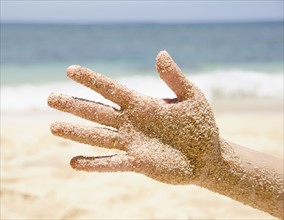 Woman's hand with sticking sand . Photo : Jamie Grill