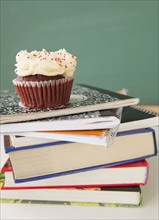 Studio shot of cupcake on stack of books. Photo : Jamie Grill